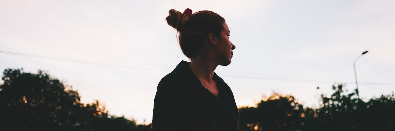 What People Don't Understand About Living With Mental Illness Young woman looking at sunset