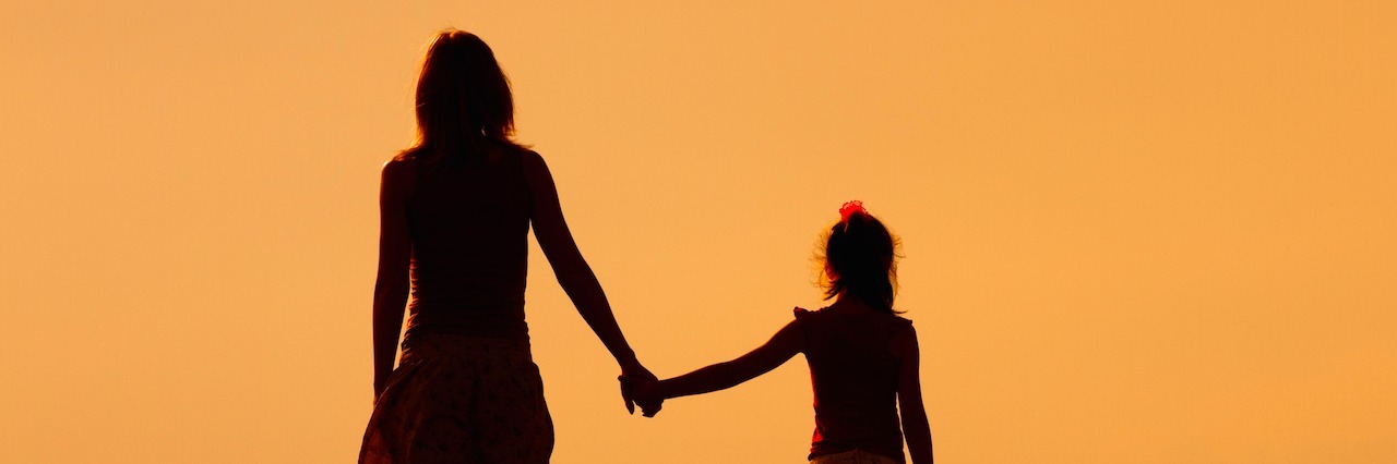Silhouette of a woman holding hands with her daughter