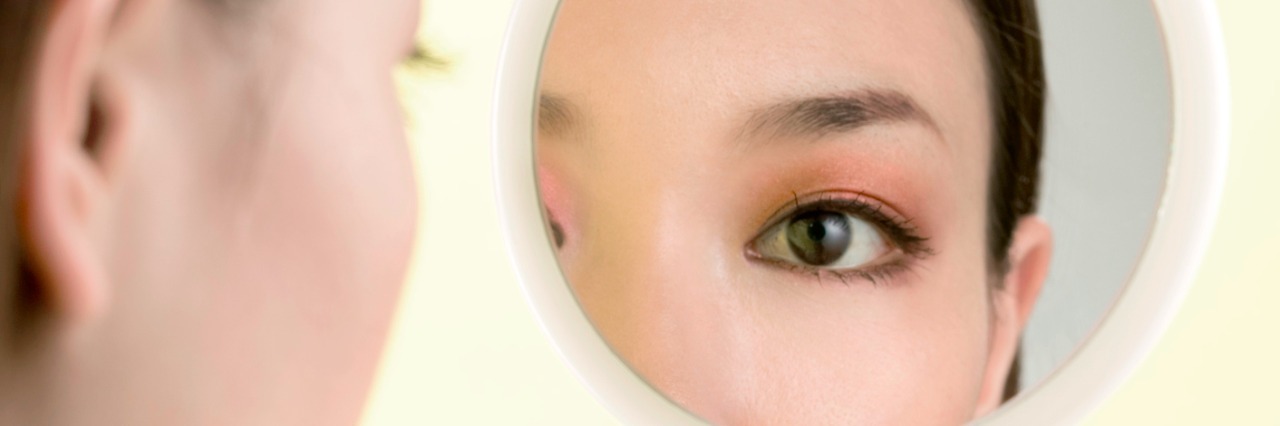 Eating Disorder Recovery: When 'Before' Feels Like a Different Life a close up of a woman looking at herself in a small handheld mirror