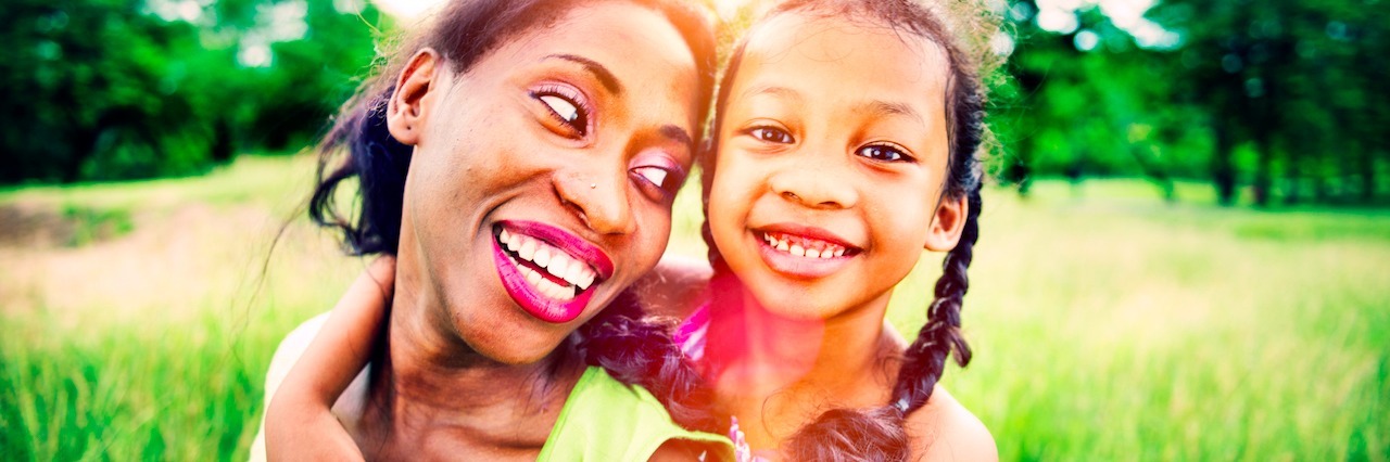 Parent With Schizophrenia: A Message From Someone Who's Been There a woman giving her daughter a piggy bag ride, outside in a field of grass