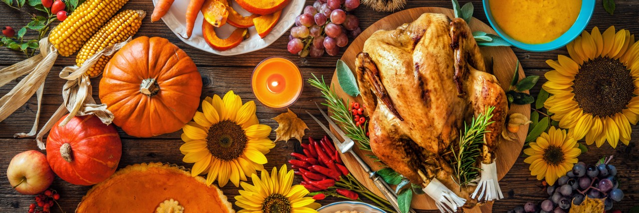 Thanksgiving With a Child With Sensory Processing Disorder Thanksgiving dinner. Roasted turkey with pumpkins and sunflowers on wooden table