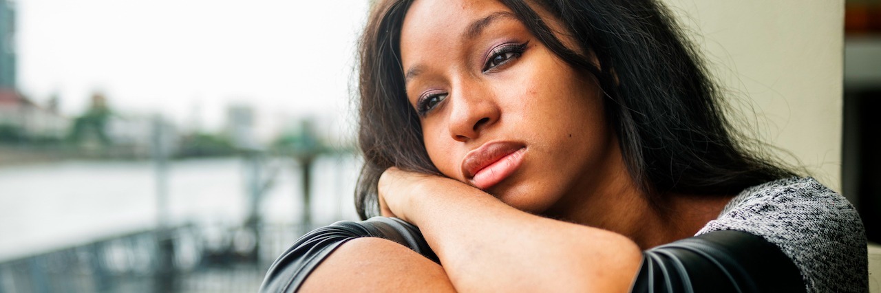 Growing Up With Depression and Social Anxiety as a Black Woman A woman leaning on a railing looking outside