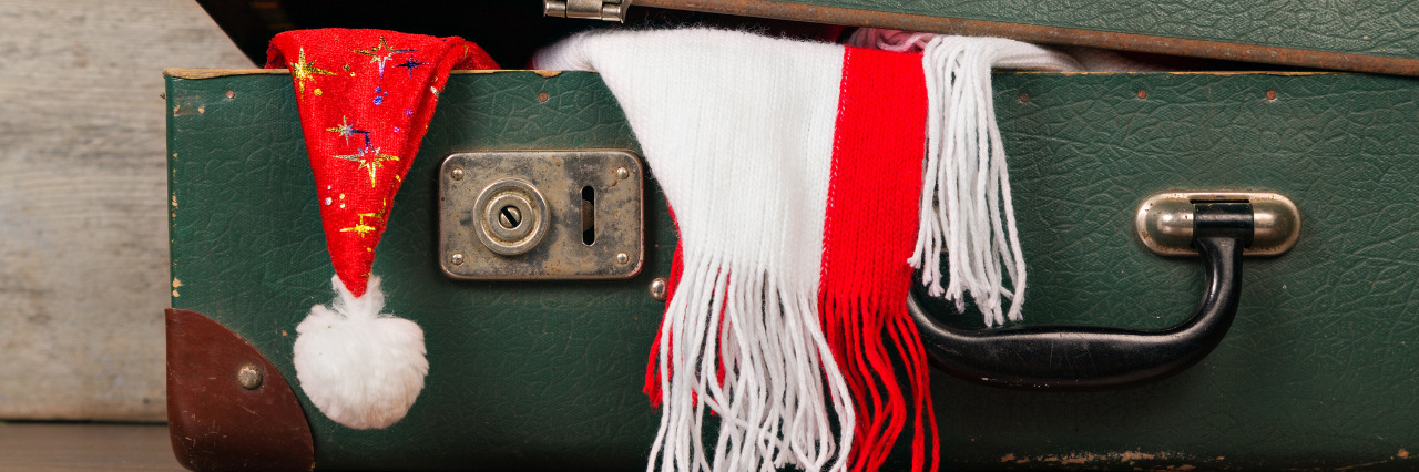 Tips for Holiday Travel With a Disability Suitcase with holiday hat and scarf.