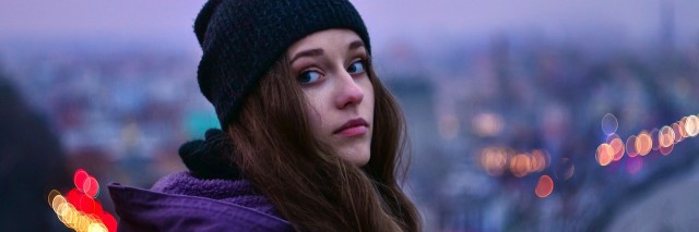 A girl in a beanie looking out at a city