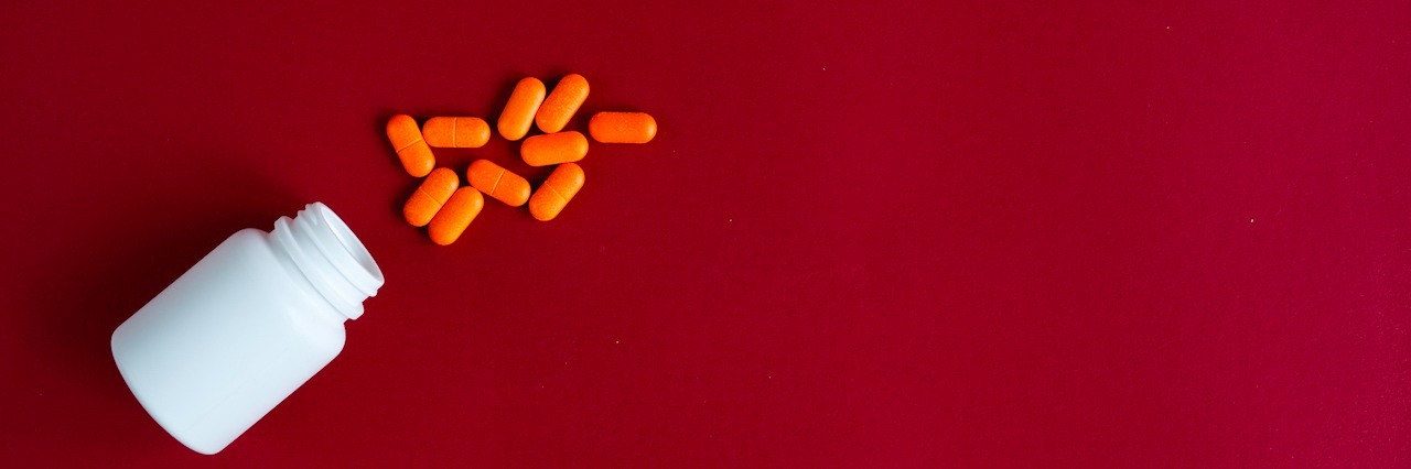 What People Don't Understand About Taking Adderall for ADHD orange tablets in plastic container on red background top view