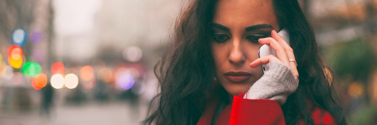 Tips for Getting Through the Holidays With SAD a sad woman on her phone outside in wintertime