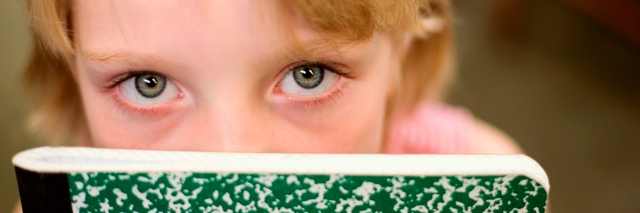 Panic Attacks in Children: What I'd Tell My Past Self Girl peeking over top of notebook