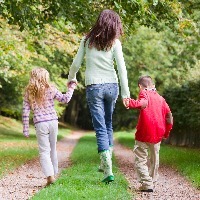 mother and two children walking on woodland path in autumn
