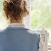 Woman using sewing machine in front of window