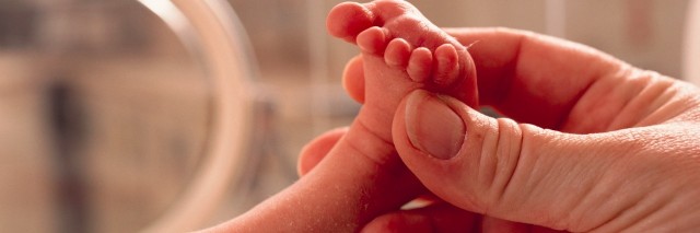 Parent holding baby's foot in NICU