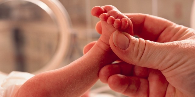 Parent holding baby's foot in hospital