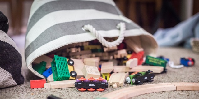 Bag full of children's toys laying on the floor with toys spilling out.