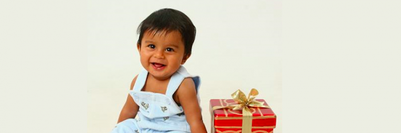 19 Gift Ideas for Children With Sensory Needs baby boy sitting next to christmas present box