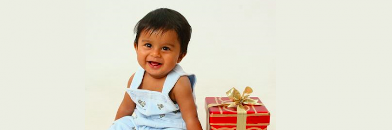 baby boy sitting next to christmas present box