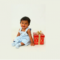 baby boy sitting next to christmas present box