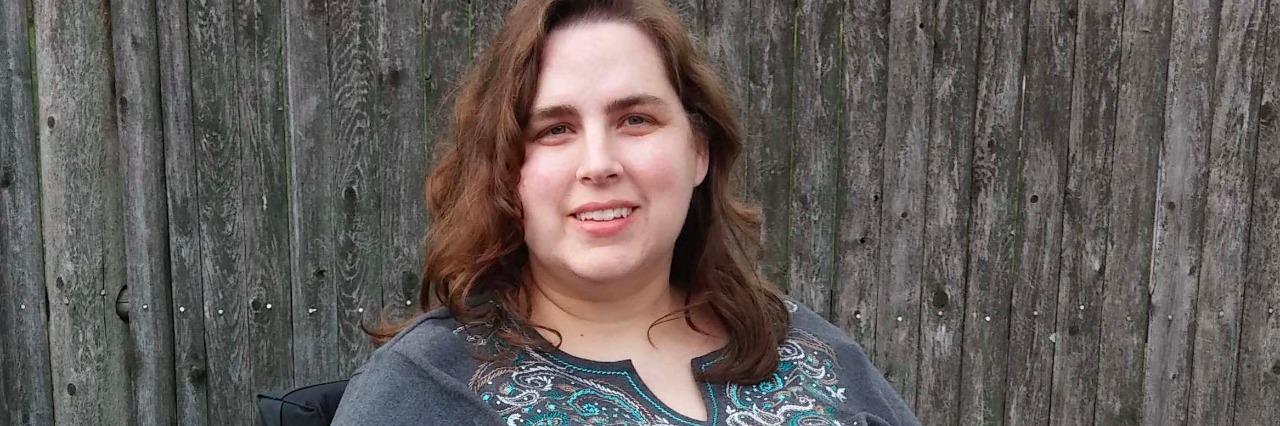 How to Help Rare Disease Patients and Research woman sitting in wheelchair in front of wooden fence