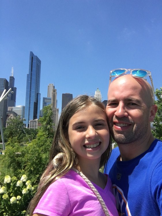 Man and daughter smiling with city skyline in background