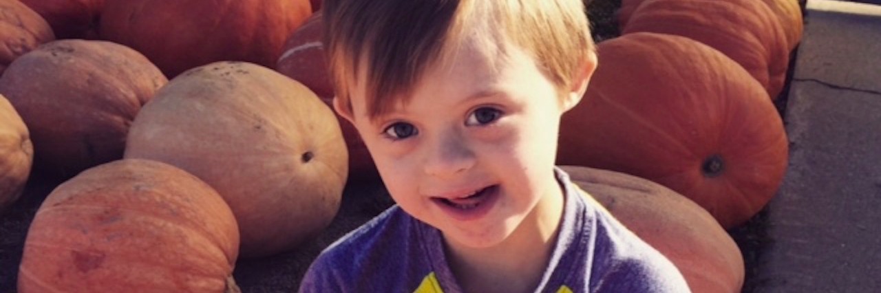Down Syndrome Parenting: What I Wish I Knew When My Baby Was Born a boy sitting in a pumpkin patch