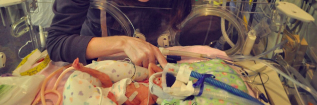 My Experience Having a Premature Baby in the NICU Mom looking at her baby in a NICU isolette