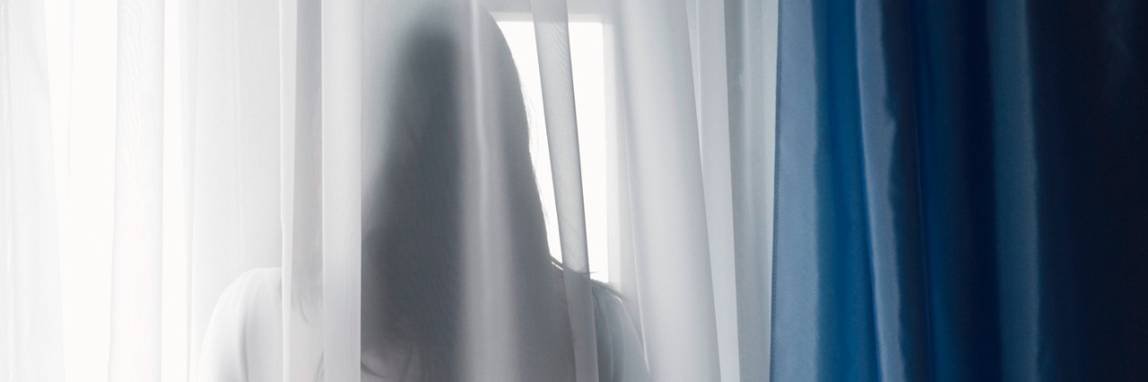 Limitations and Disappointments of Living With Chronic Pain Woman looking through window, back view