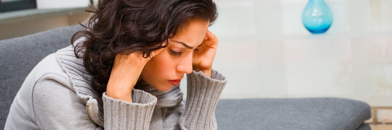 To Those Who Give Medical Advice for Migraines woman holding head sitting on couch