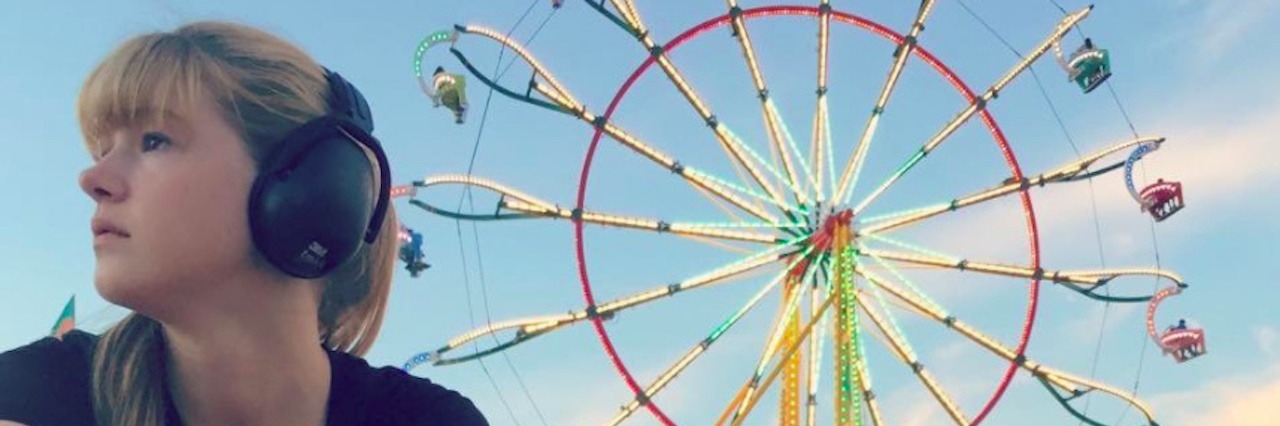 Responding to Judgment as an Adult With Sensory Processing Disorder The author and her service dog sitting on the grass in front of a ferris wheel
