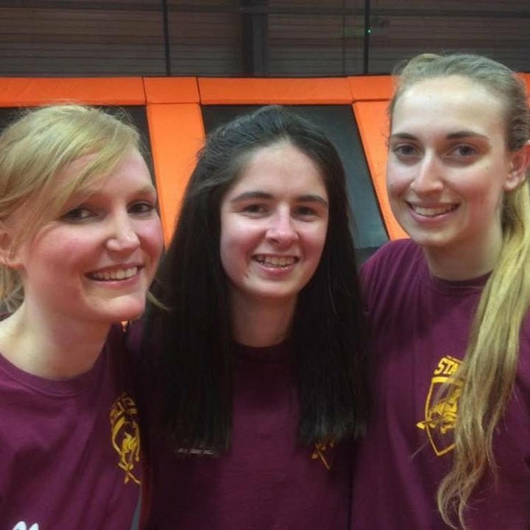 three friends in matching maroon shirts smiling backstage during a film shoot