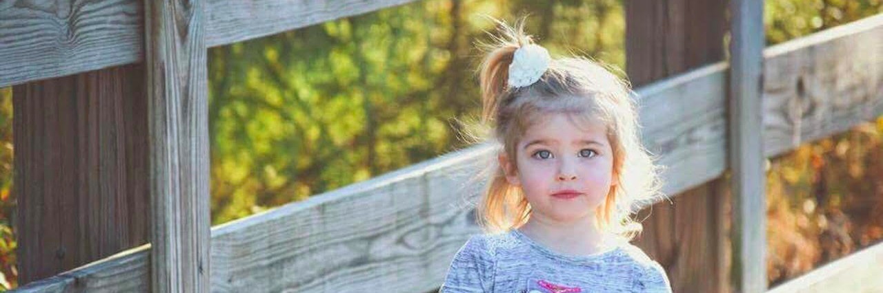 What I Want to Be Asked About My Daughter on the Autism Spectrum young girl in front of wooden fence