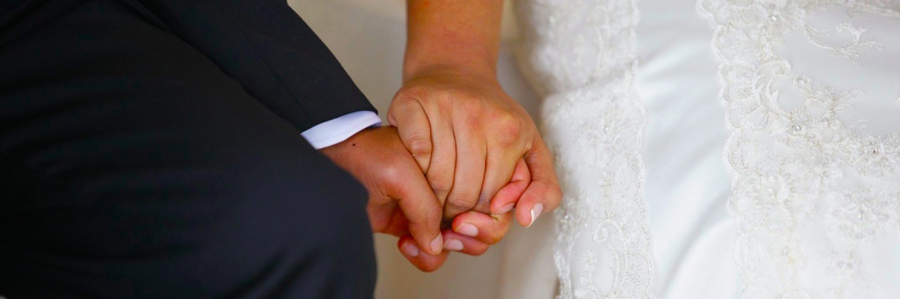 Husband and wife holding hands during a wedding ceremony