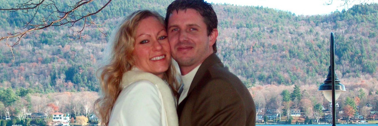 Anniversary Letter to My Husband, From Your Wife With Chronic Illness Man and woman hugging, facing the camera, against a view of the water