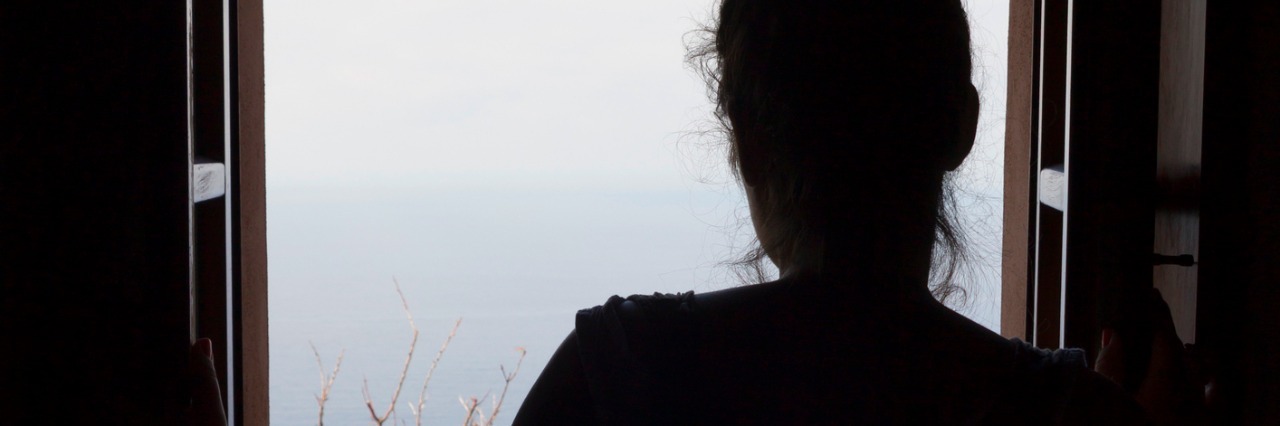 8 Things to Know About People Living With Chronic Health Conditions Woman looking through the window