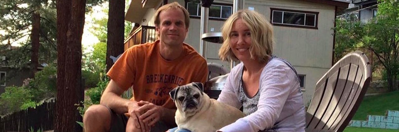 man and woman sitting outside on a patio with their pug