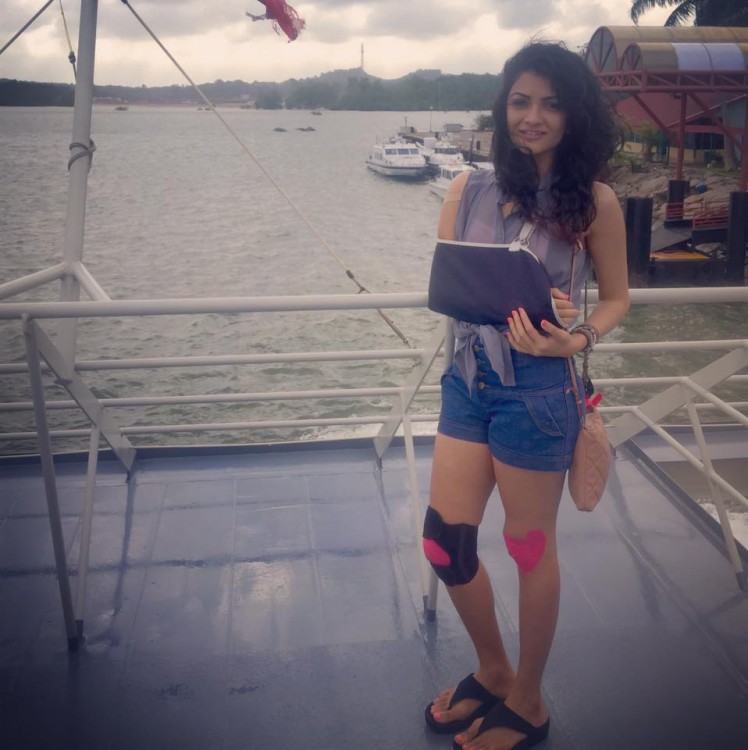 woman standing on boat wearing sling on arm and tape on knees