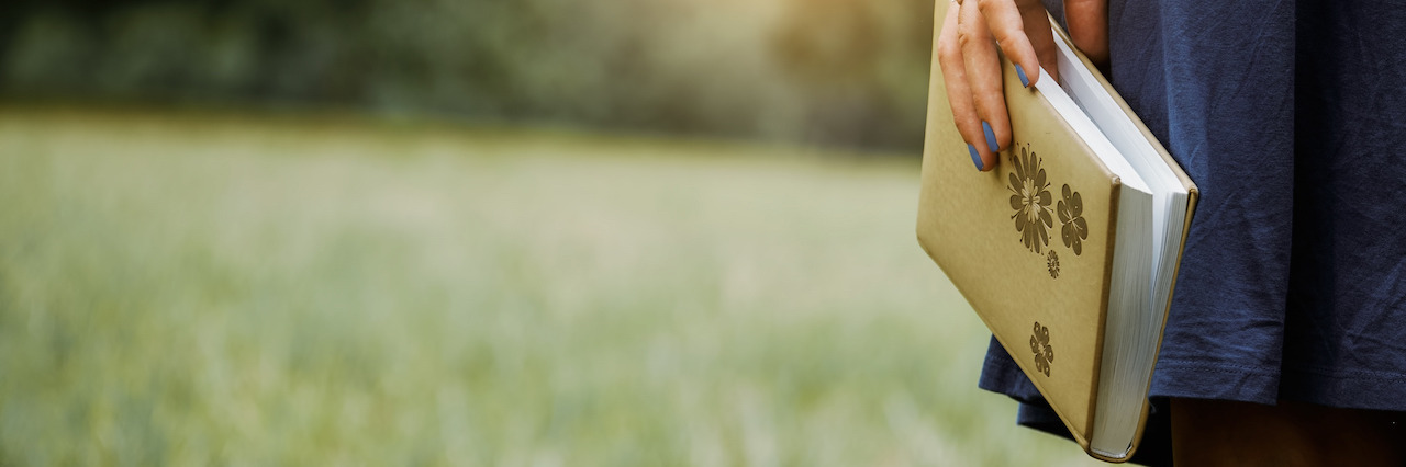 How Bullet Journaling Can Help With Self-Care The side view of a woman holding a journal