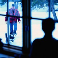 boy watching a man a dog in the snow through a window