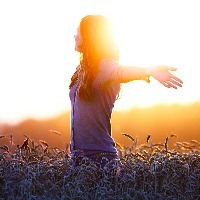 woman raising her arms in a field