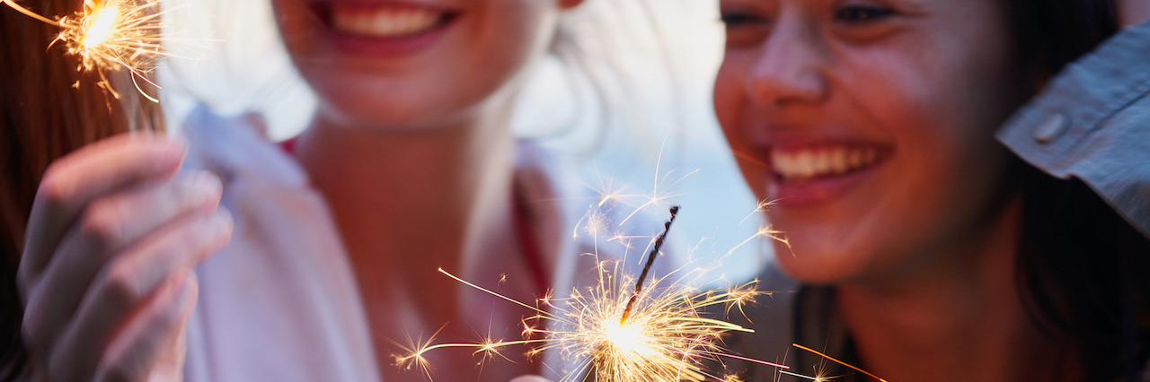 Teenage girls celebrate and smile with sparklers close up shot