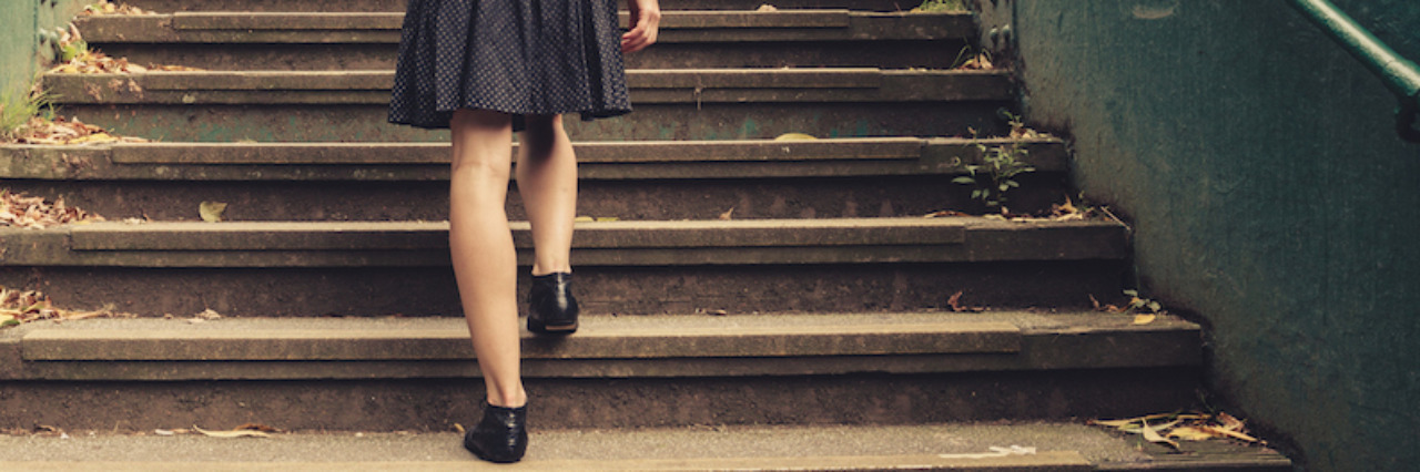 A young woman is walking up stairs outside in a park