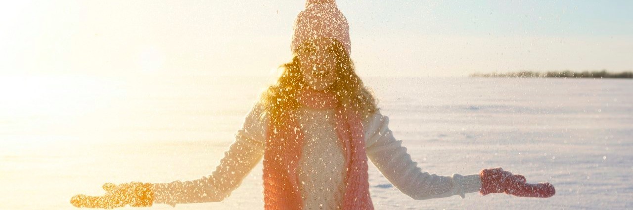 young woman throws snow on winter field