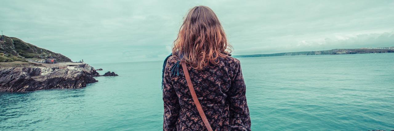 4 Lessons I Learned After a Suicide Attempt A young woman is sitting by the water's edge in a harbour
