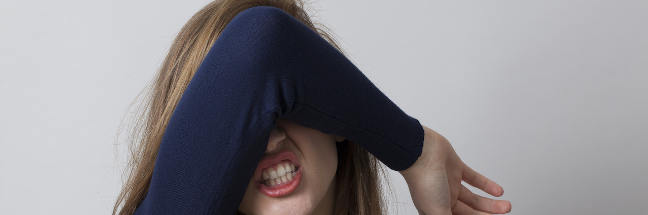 A woman covering her face with her arm in frustration