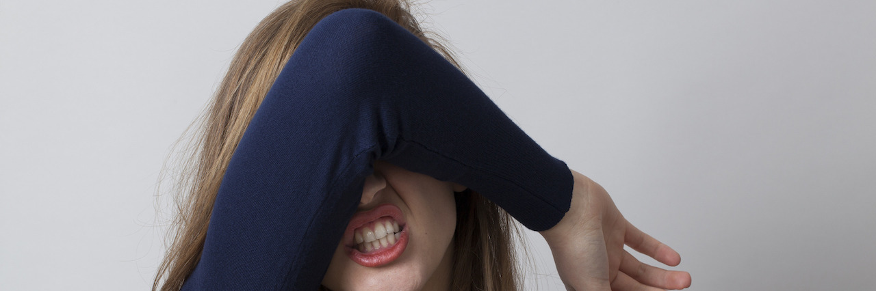 To the Person Who Used My Mental Illness as an Adjective A woman covering her face with her arm in frustration