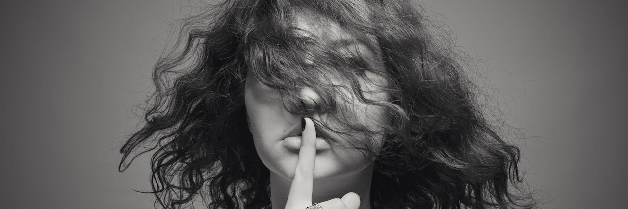 Melancholic woman holding finger on her face over gray background
