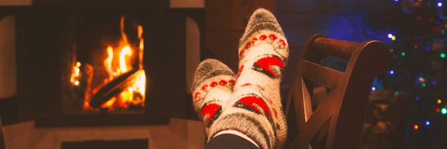 woman is warming her legs near the fireplace in winter socks during the cristmas holidays