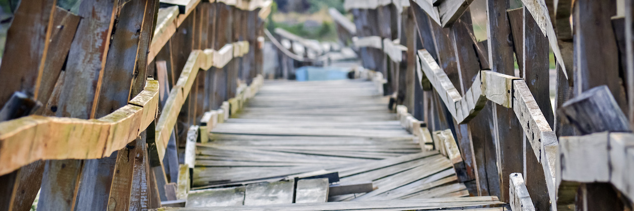 When Recovery From Anorexia Is Not a Straight Path Closeup of a deformed and dilapidated wooden bridge over the small river. Weathered and broken wood planks of a very old and damaged pedestrian bridge near the village.