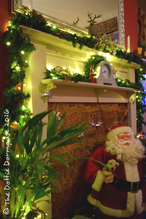 mantel decorated for christmas with garland, ornaments, and a santa