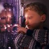 young boy sitting next to window fairy lights