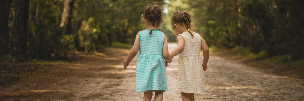 Having Support of Sisters During Battle With Crohn's Disease Sisters walking in the woods away from the camera.
