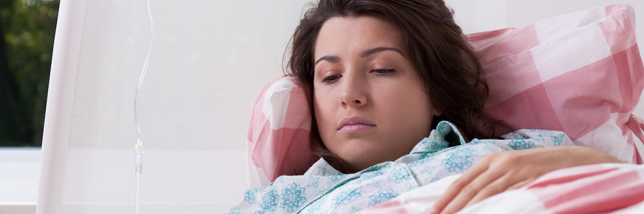 Young woman lying in hospital having intravenous therapy