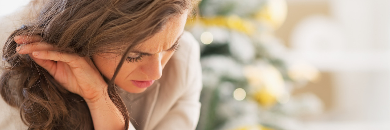 5 Ways to Get Through the Holiday Season With Mental Illness Stressed young woman in front of christmas tree